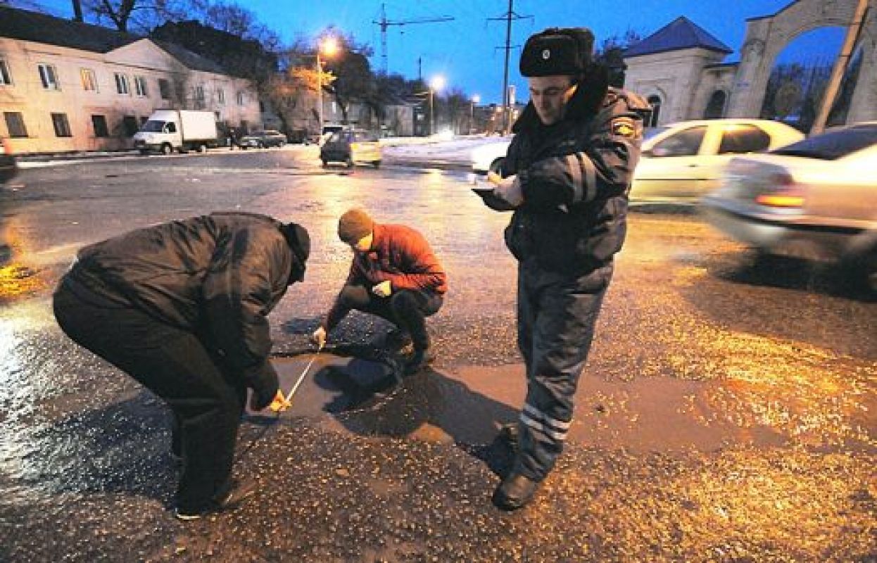 Пострадавшие автомобилисты измеряют размеры ямы
